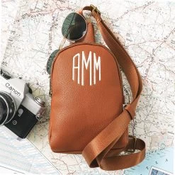 Monogrammed Sling Bag -Fashion Clothing Store Cyy tan sling bag on top of map